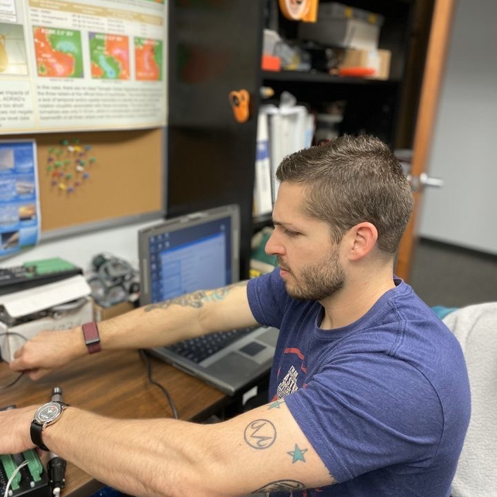 L'SPACE student Lance Belobrajdic in the Atmospheric Sciences Department Radar Room in the College of Geosciences configuring a CRX-1000 Data logger for the Texas A&M University Research Farm Mesonet Weather Station.