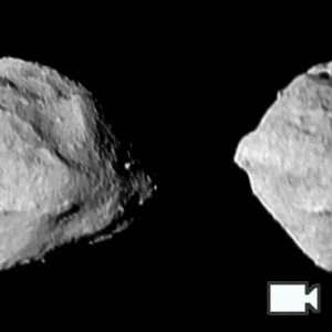 Two almost identical gifs of Selam (two connected rocks) side by side. It is rotating left to right. One of its nodes is moving behind to foreground rock. It is lit from the right with harsh shadows.